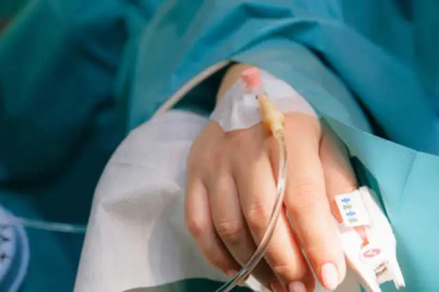 Hand with IV draped in a medical gown.